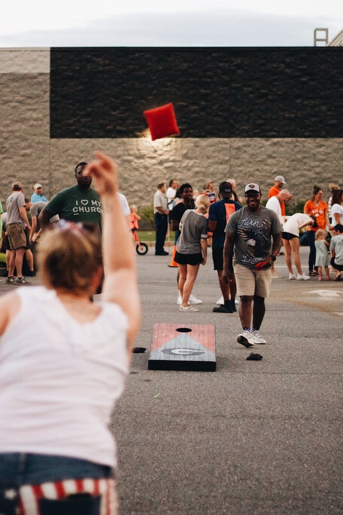 Community members engage in an exciting cornhole game during an outdoor gathering.