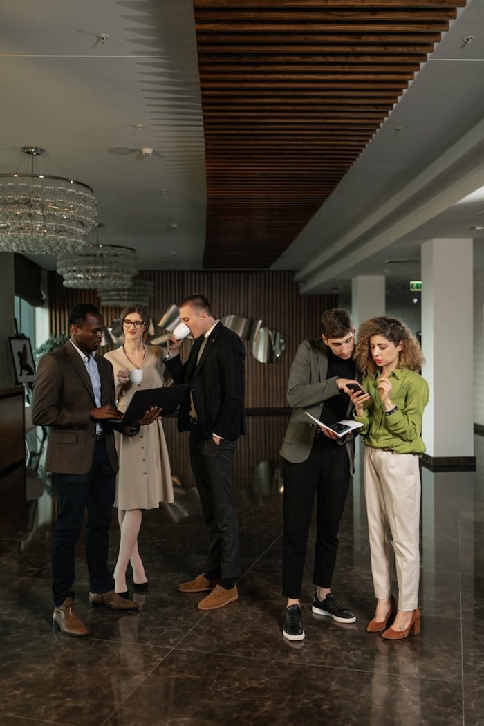 A group of colleagues discussing work in a modern office lobby, showcasing diversity and teamwork.